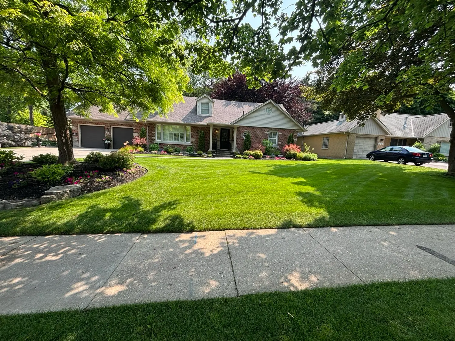 Lush manicured front lawn and garden beds